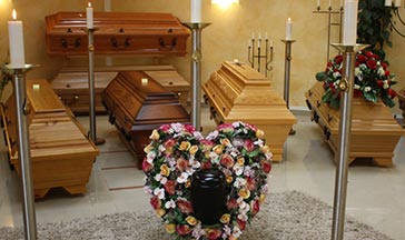 Särge und Urne mit Blumenkranz